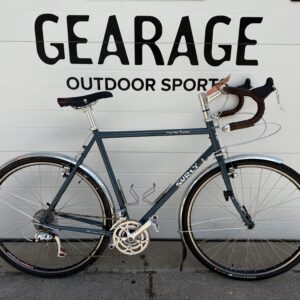 Surly Long Haul Trucker, grey, sits in front of The Gearage's garage door